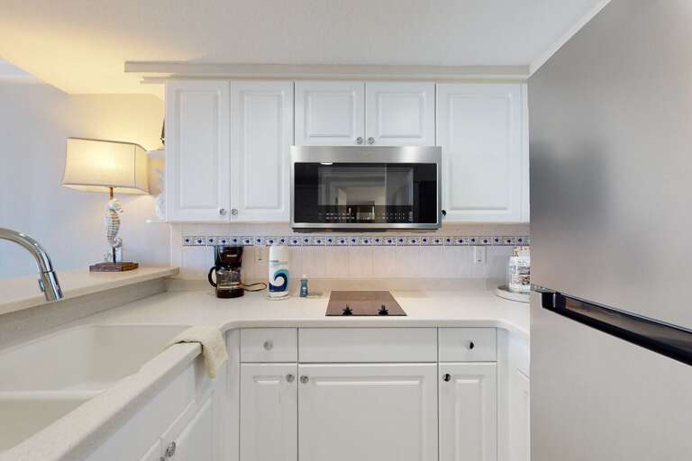 Bright, Pristine Kitchen With White Cabinetry And Sleek Surfaces In Vacation Rental