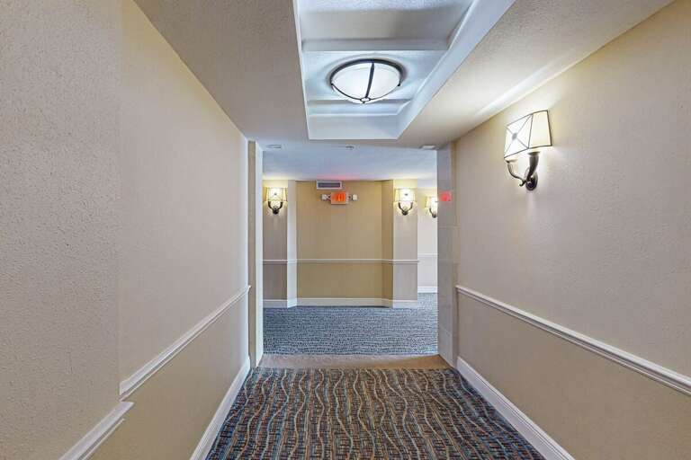 Lit Hallway Tapering To Bright Exit Doors