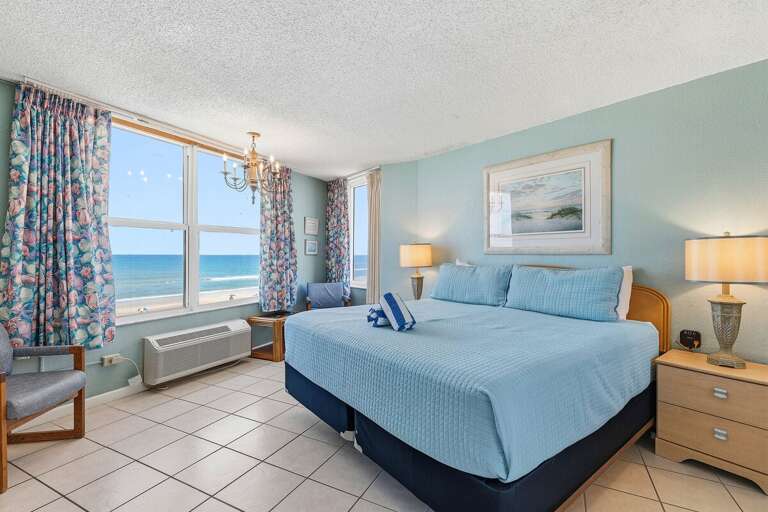 Wake up to breathtaking ocean views in this spacious king bedroom featuring large windows, coastal
