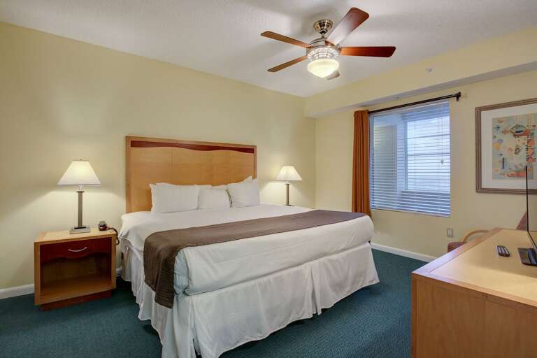 Comfortable beach-inspired king bedroom with soft lighting, warm tones, and plenty of space—ideal for unwinding after a relaxing day by the ocean.