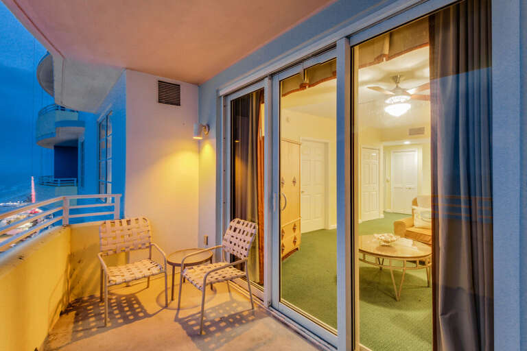 Inviting beach stay balcony with warm evening lighting, comfortable seating, and stunning ocean views—perfect for relaxing after a day of sun, sand, and surf.