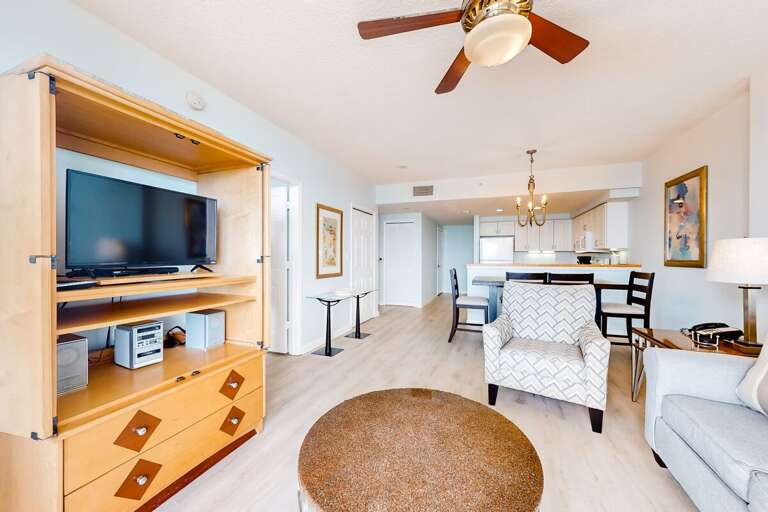 Relax in this airy beach-stay living space featuring comfy seating, ocean-inspired décor, and an open layout leading to the kitchen—perfect for unwinding after a day on the shore.