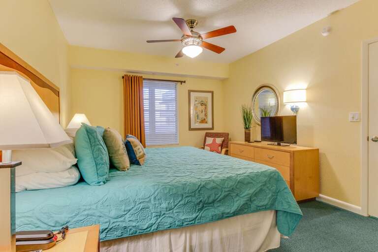Relax in this bright beach-inspired bedroom featuring a plush king bed, tropical décor, and ample natural light—perfect for unwinding after a sun-soaked day at your oceanfront getaway.