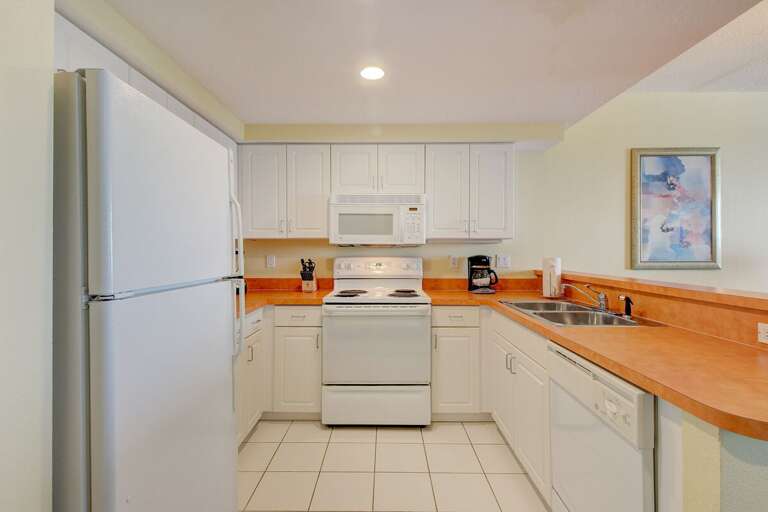 Spacious beach stay kitchen featuring crisp white cabinets, full appliances, and ample counter space—perfect for preparing seaside meals before heading back out to the shore.