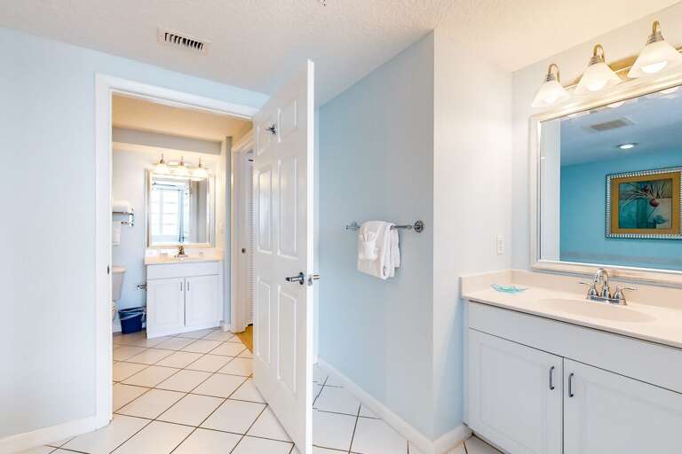 Spacious beach-style bathroom featuring dual vanities, fresh towels, and clean tile floors. Enjoy a relaxing retreat after sun-filled days at your beachfront stay.