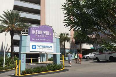 Palm-lined Path To A Towering Resort With Prominent Signage
