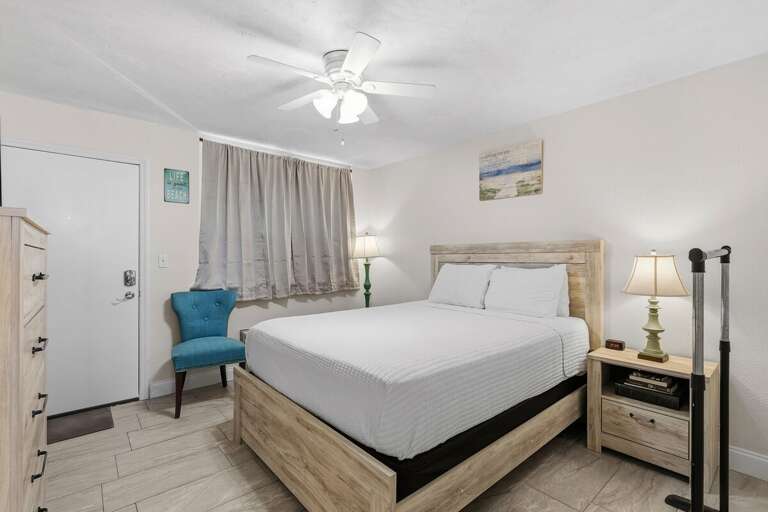 Interior Bedroom With Bright Bedding, Blue Chair, And Wooden Furniture