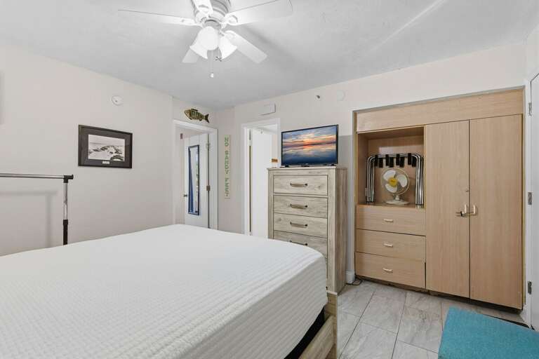 Bedroom With White Walls, Wooden Wardrobes, And Beach-themed Decor