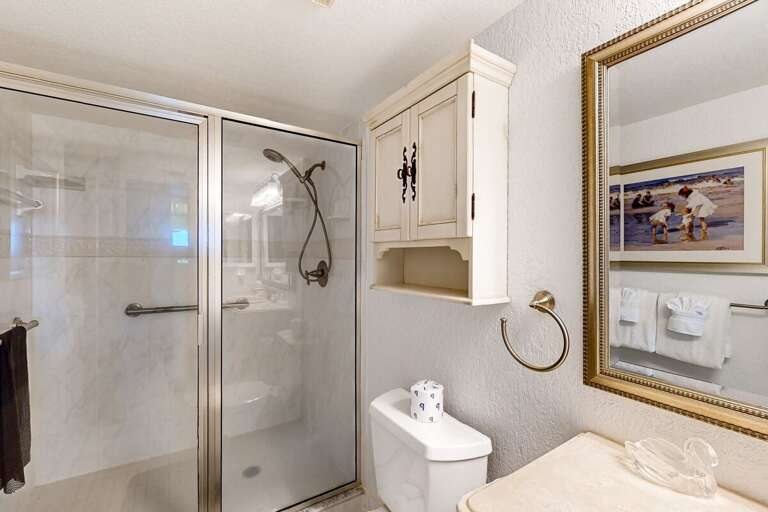 This bright bathroom offers a walk-in shower, classic coastal décor, and essential amenities—providing comfort and convenience throughout your relaxing beach stay.