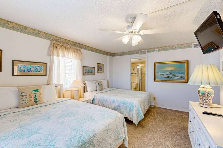 Charming guest bedroom featuring two comfy beds, soft coastal décor, and plenty of space—perfect for families enjoying a relaxing beach stay.