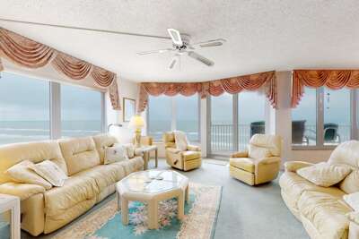 Relax in this bright oceanfront living room featuring plush seating, sweeping beach views, and coastal charm—perfect for a serene beach stay.