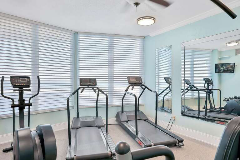 Stay active during your beach stay in this well-equipped fitness room featuring treadmills, cardio machines, and large windows that fill the space with natural coastal light.