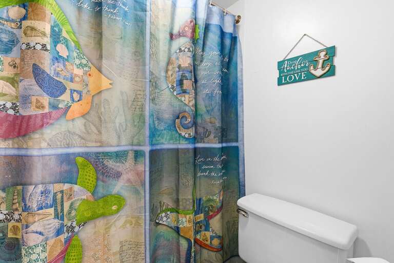 Add charm to your beach stay with this vibrant coastal-themed bathroom featuring a colorful