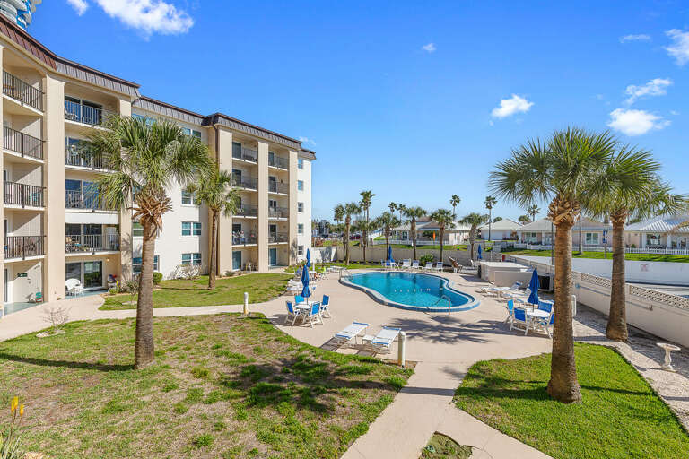 Experience the perfect beach stay with this palm-lined pool area featuring lounge seating and sunny skies. A relaxing retreat to swim, unwind, and enjoy coastal living just minutes from the beach.