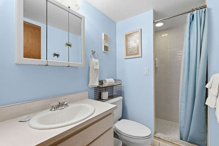 Freshen up during your beach stay in this bright bathroom featuring a walk-in shower, clean finishes, and coastal touches. A convenient and comfortable space to recharge after a day at the beach.
