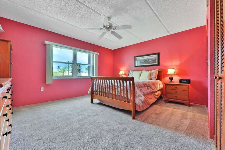 Vivid Vermilion Vacation Rental Room With Wooden Bed And White Carpet
