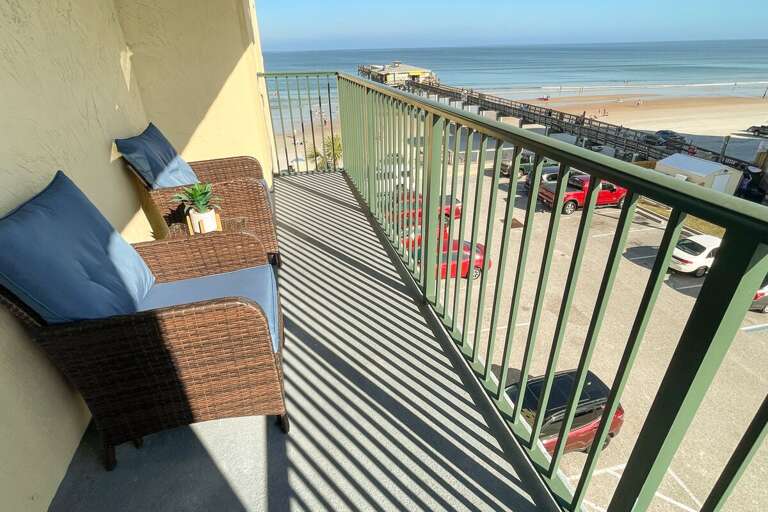 Balcony View Of Beach With Wicker Chair And Pillow