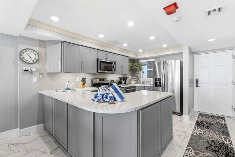 Cook with ease in this modern beach condo kitchen featuring stainless steel appliances, quartz