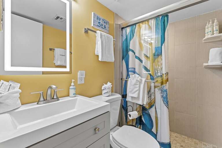 Freshen up in this bright coastal bathroom featuring a modern vanity, walk-in shower, fresh towels,