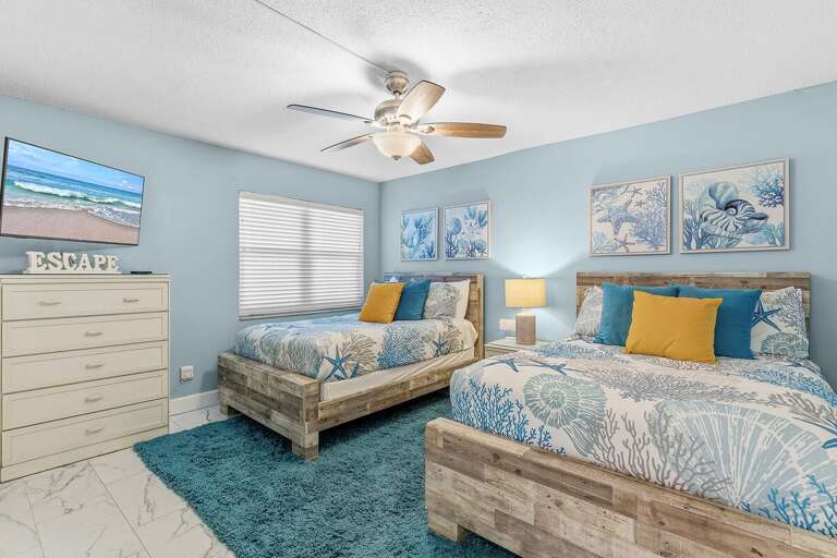 Perfect for families or friends, this coastal guest bedroom features two queen beds, a Smart TV, and