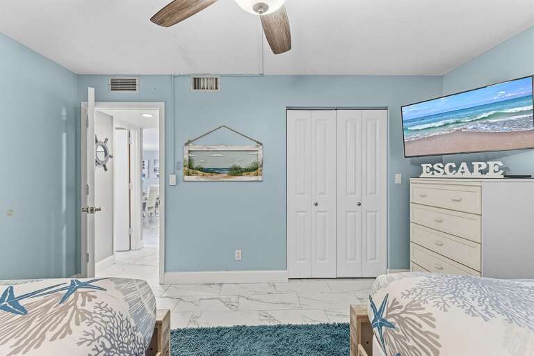 This spacious guest bedroom features two queen beds, a Smart TV, coastal décor, and ample storage.