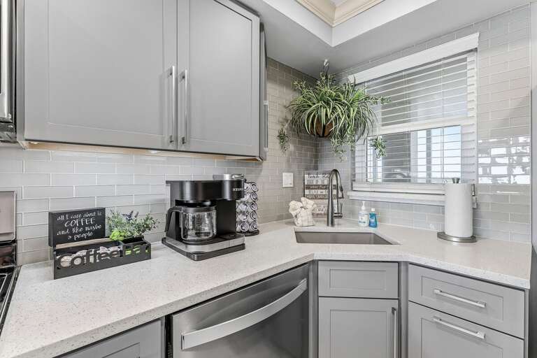 Start your beach day at the dedicated coffee station in this modern kitchen featuring quartz