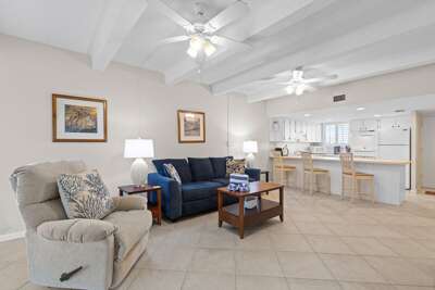 Relax in this open beach-style living area with cozy seating and a spacious kitchen and bar. Perfect for unwinding after a sunny day by the shore.