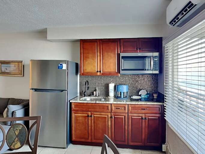 Enjoy the convenience of a fully equipped kitchenette with stainless steel fridge, microwave, and coffee maker—perfect for quick meals during your relaxing beach stay.