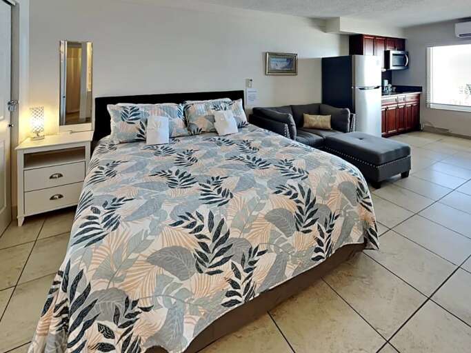 Rest easy in this inviting beach retreat featuring a plush king bed, cozy seating area, and convenient kitchenette—ideal for unwinding after sun-filled days by the shore.