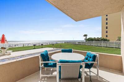 Relax in comfort on this cozy patio with turquoise cushions, offering stunning ocean views and easy beach access, perfect for peaceful moments and memorable seaside gatherings.