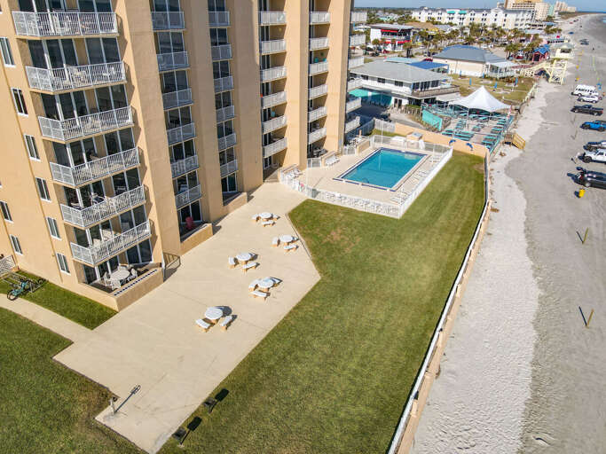Expansive patio with seating areas for gatherings, blending seamlessly into grassy lawns and oceanfront charm.