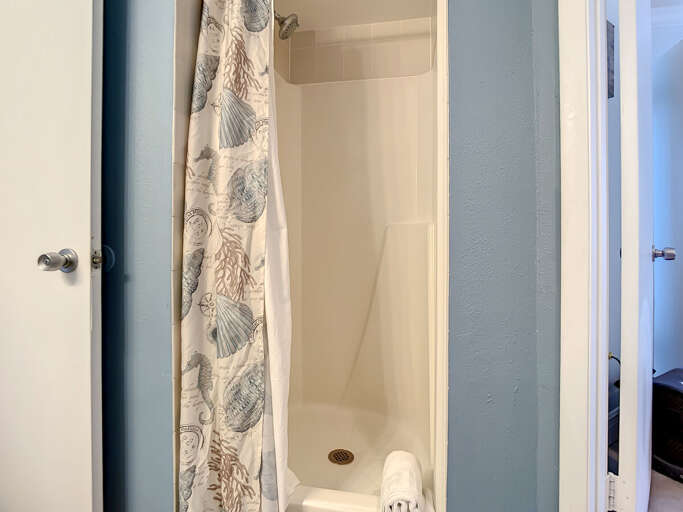 Walk-in shower with elegant coastal-themed curtains, creating a soothing retreat after a day at the beach.
