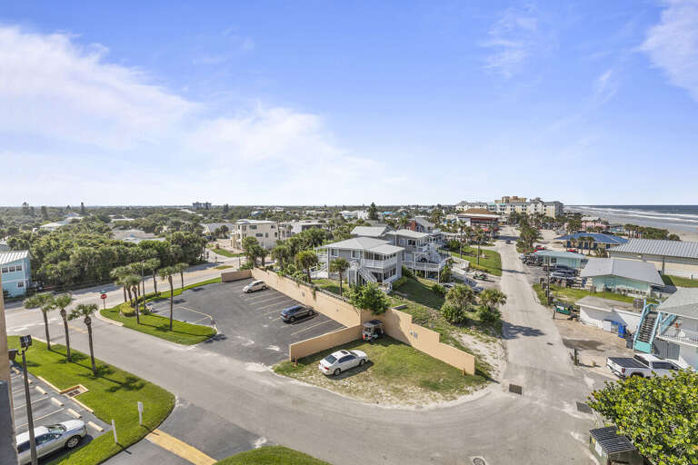 This captivating aerial shot captures a peaceful coastal neighborhood, with charming homes and lush greenery. The view extends toward the ocean, offering a glimpse of the nearby beach.