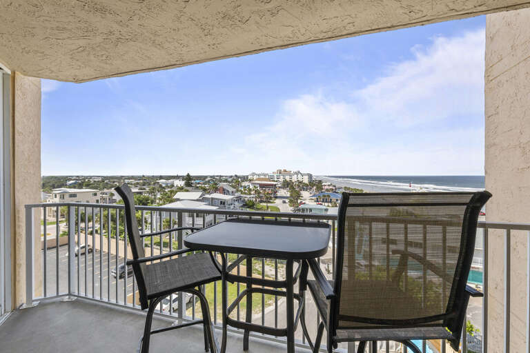 A comfortable patio table and chairs invite you to sit and enjoy the expansive view of rooftops and winding roads leading to the ocean in the distance.