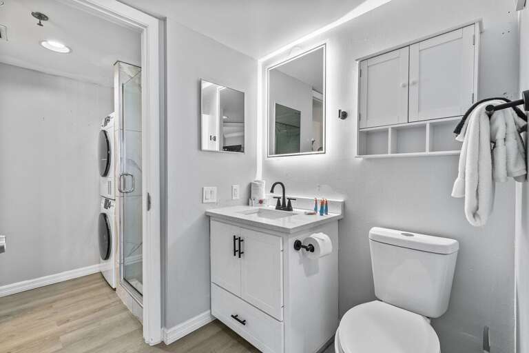 The minimalist design is complemented by the adjacent glass-enclosed shower. For added convenience,