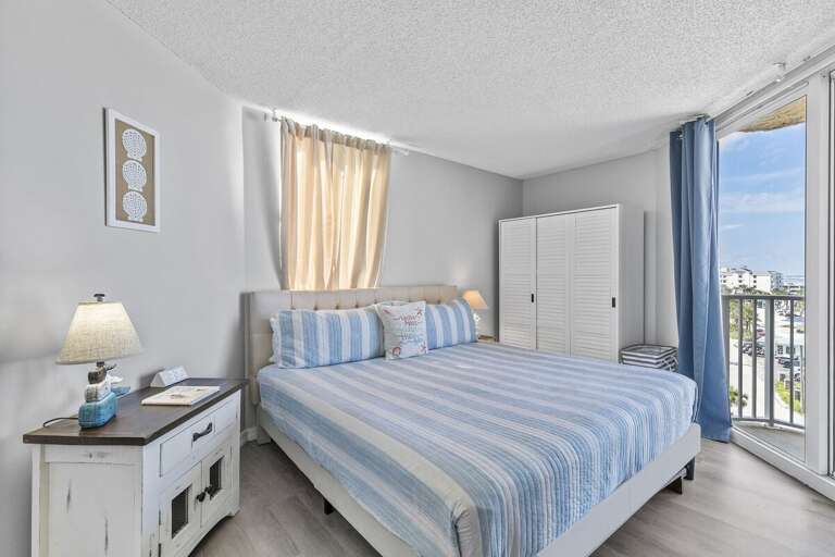 This serene bedroom features soft, coastal-inspired decor with light blue and white striped bedding that complements the oceanic theme.