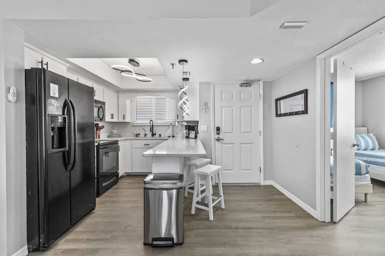 his sleek, modern kitchen showcases a clean design with white cabinetry, a black refrigerator, and