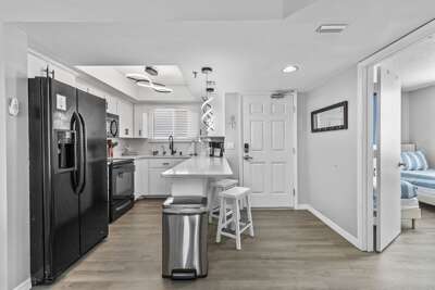 his sleek, modern kitchen showcases a clean design with white cabinetry, a black refrigerator, and