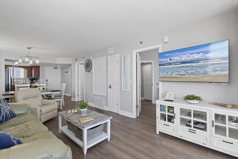 Spacious living area with modern decor, comfortable seating, and a large TV.