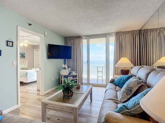 Cozy living space with ocean views, direct balcony access, and a glimpse into the charming bedroom for a seamless coastal retreat.
