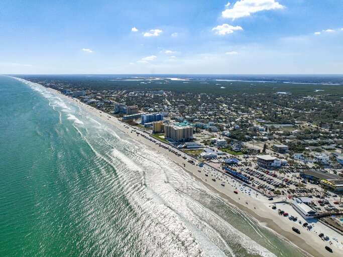 Dynamic shoreline buzzing with activity, scenic coastal neighborhoods, and shimmering waves under the sun.