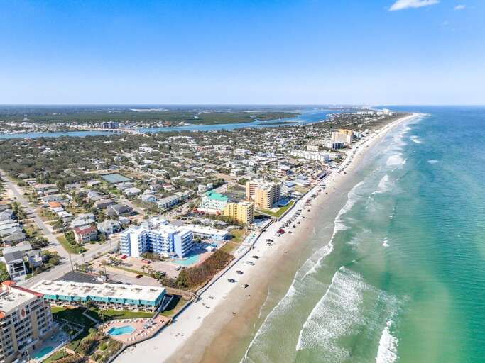 Overhead perspective highlighting a harmonious blend of coastal residences and serene sandy beaches.