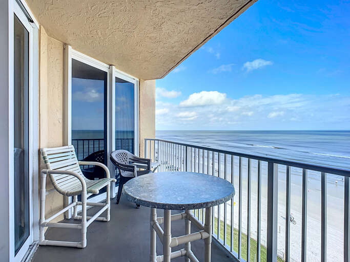Relax on a spacious balcony featuring comfortable seating and breathtaking panoramic views of the beach and ocean. Perfect for unwinding.
