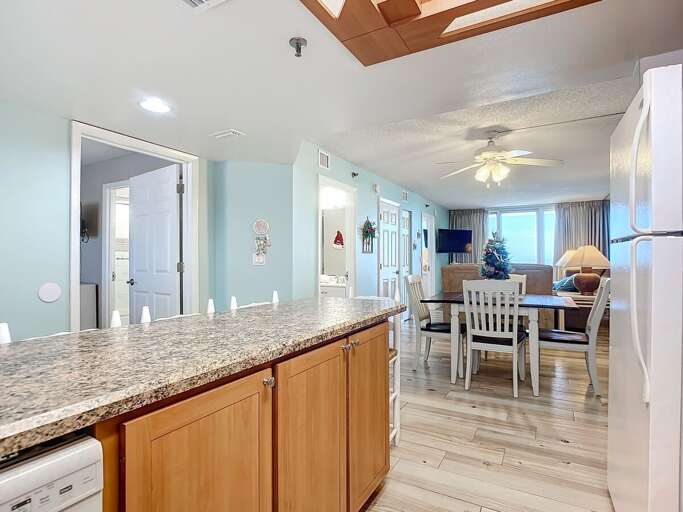 Spacious layout connecting the kitchen to a cozy dining and living area, featuring natural light, festive decor, and comfortable seating for a welcoming atmosphere.