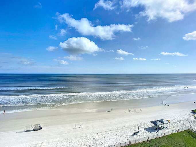 Stunning view of the sandy shoreline and sparkling ocean waves under a bright blue sky. Perfect for beach lovers and relaxation seekers.