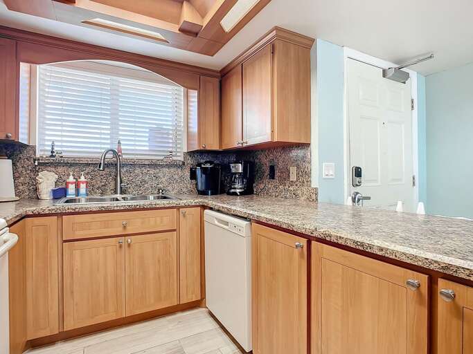 Sunlit kitchen features granite countertops, modern fixtures, and custom wood cabinets. Perfect for preparing meals and enjoying a cozy, welcoming atmosphere.