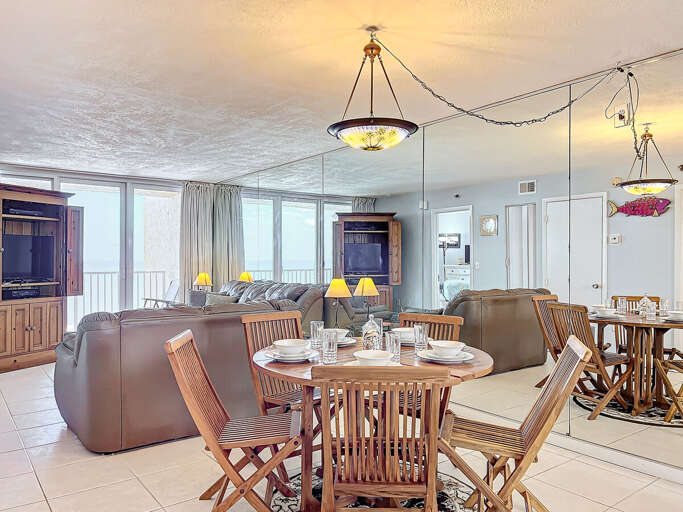 Gather for meals in this stylish dining space, surrounded by natural light, comfortable seating, and a mirrored wall enhancing the coastal ambiance.