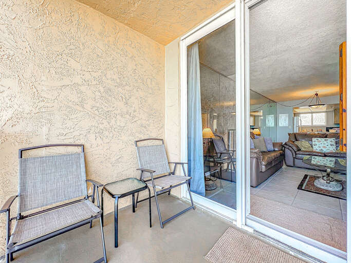 This intimate balcony features comfortable seating and direct access to the living room, providing a perfect spot to unwind and enjoy the coastal ambiance.