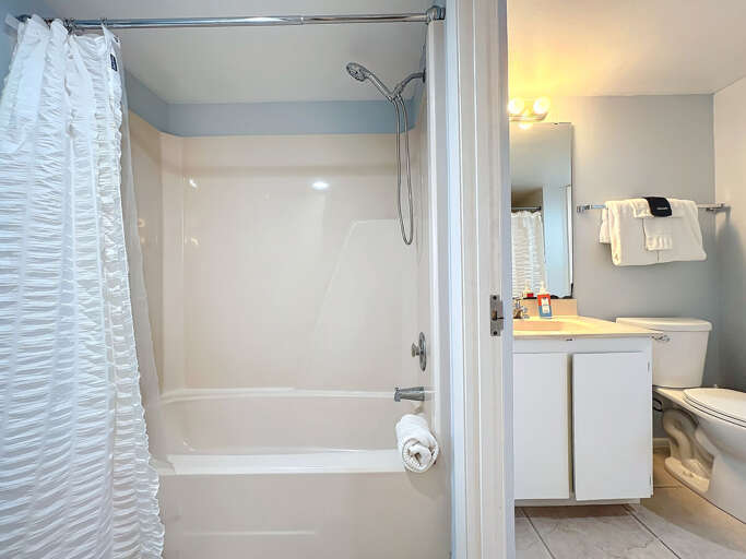 This inviting bathroom features a clean shower-tub combo, ample counter space, and bright lighting for a comfortable and convenient stay.