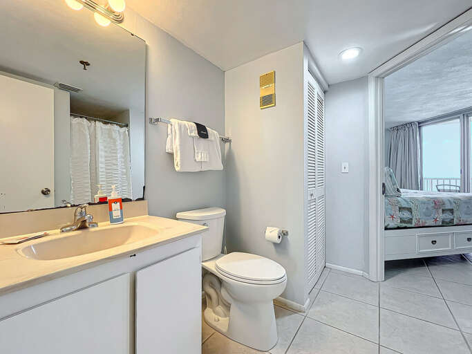 This well-lit bathroom features a spacious vanity, modern fixtures, and convenient access to the adjoining bedroom for ultimate comfort.
